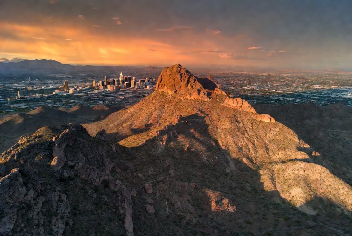 Aerial view of Phoenix, Arizona skyline at sunset with Piestewa Peak in the foreground